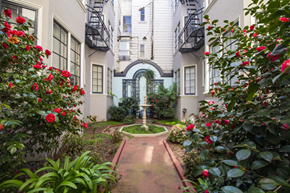 San Francisco apartment for rent - Charming apartment courtyard with lush greenery, red flowering plants, and an arched entryway leading to a fountain