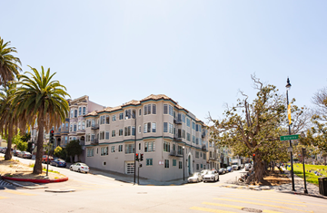 San Francisco apartment for rent - A street view of a residential area with apartment buildings, cars, and palm trees.