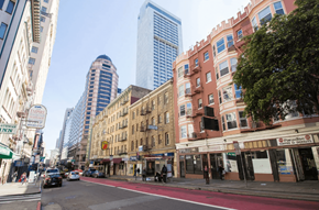 San Francisco apartment for rent - A city street with a mix of old and new buildings, cars on the road, and a pedestrian crossing.