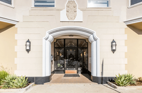 San Francisco apartment for rent - A beige building with a black door and a white archway above it.