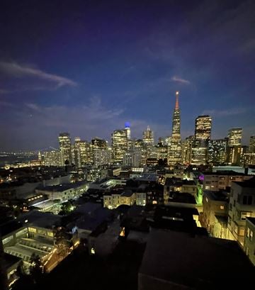 San Francisco apartment for rent - A cityscape at night with a tall building lit up in blue and orange.