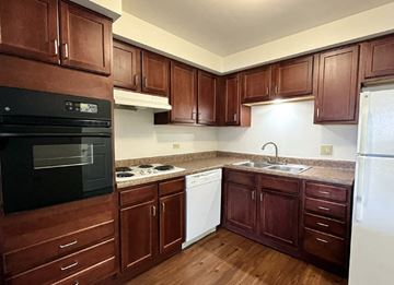 Littleton apartment for rent - A kitchen with dark wood cabinets and appliances.