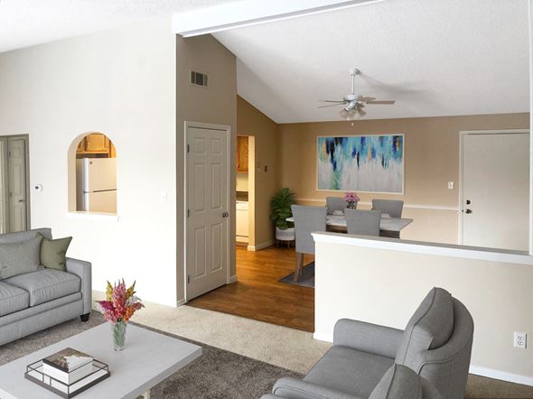 Orchard Park apartment for rent - A living room with a grey couch, a grey chair, a white coffee table, a painting on the wall, and a ceiling fan.