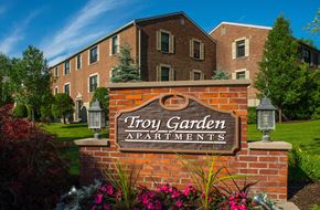 Troy apartment for rent - a sign for try garden apartments in front of a brick building