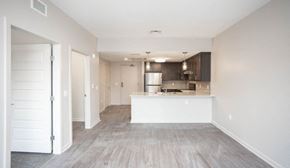 Irondequoit apartment for rent - an empty living room and kitchen with white walls and wood flooring