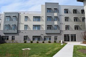 Rochester apartment for rent - A modern building with grey and white exterior and a green lawn in front.