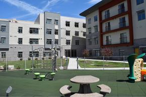 Rochester apartment for rent - A playground with a green slide and a red and white building in the background.