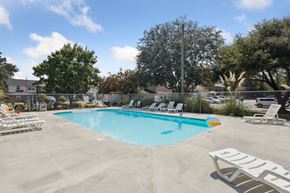 Statesboro apartment for rent - A pool with chairs around it and trees in the background.