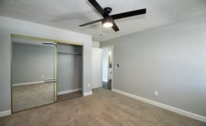 Denver apartment for rent - an empty living room with a ceiling fan and a mirrored closet