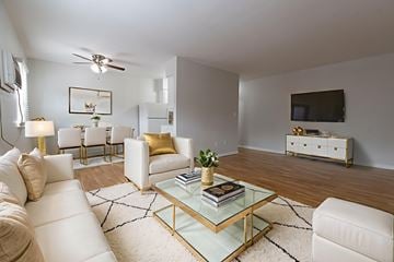 Allentown apartment for rent - A living room with a white couch, a glass coffee table, and a television on the wall.