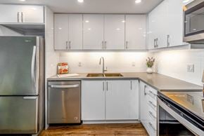 Mississauga apartment for rent - L-shaped kitchen with white glossy cabinets, refrigerator, and dishwasher.