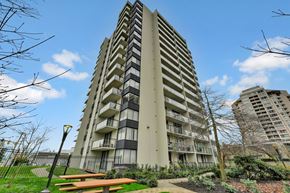 Burnaby apartment for rent - A tall residential building with balconies and a park in front.