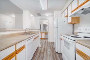 San Antonio apartment for rent - A kitchen with white appliances and wooden accents at The Villages at Lost Creek Apartments, San Antonio, Texas