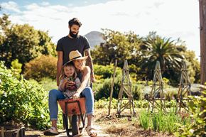 Johnson City apartment for rent - A man and a child are riding a tricycle in a garden.