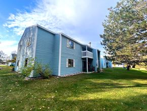 Rogers City apartment for rent - A blue house with a white porch and a tree in front.