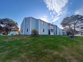 Rogers City apartment for rent - A blue building with a white balcony is surrounded by green grass.