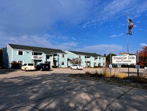 Rogers City apartment for rent - A parking lot in front of a blue building with a sign that says Presque Isle Apartments.