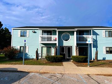Rogers City apartment for rent - A blue building with a white door and a parking space in front.
