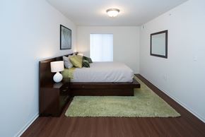 Grayling apartment for rent - A bedroom with a bed, nightstand, and two pictures on the wall.