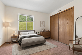 Coldwater apartment for rent - A bedroom with a large bed, a nightstand with a lamp, a chair, and a wooden wardrobe.
