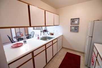 Monroe apartment for rent - A kitchen with white cabinets and a red rug on the floor.