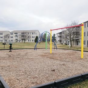 Adrian apartment for rent - A playground with a red swing set and a blue slide.