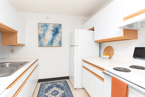Athens apartment for rent - A kitchen with white cabinets and a blue rug on the floor.