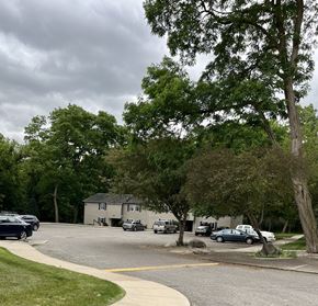 Ionia apartment for rent - a parking lot with trees and cars in front of a house