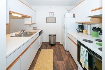 Warsaw apartment for rent - A small kitchen with white cabinets and a white fridge.