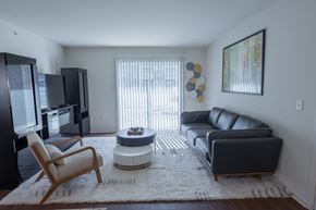 Toledo apartment for rent - A living room with a black couch, a chair, and a television.