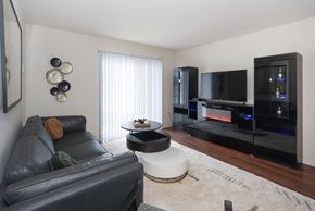Fort Gratiot Twp apartment for rent - A black leather couch sits in a living room with a television and a fireplace.