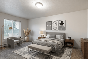 Kendallville apartment for rent - A bedroom with a large bed and a grey chair.