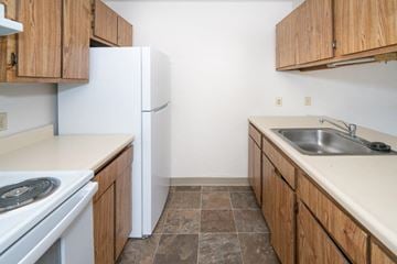Port Austin apartment for rent - A kitchen with a white fridge and wooden cabinets.