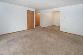 Bloomingdale apartment for rent - an empty living room with carpet and a door to a bedroom
