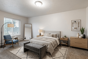 Adrian apartment for rent - A well-lit bedroom with a large bed, a chair, and a nightstand.
