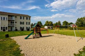 Milan apartment for rent - A playground with a green slide and a red swing set in front of a building.