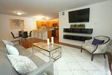 Jackson apartment for rent - A modern living room with a grey couch, a glass coffee table, and a television mounted on the wall.