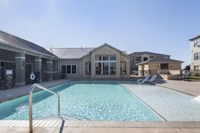 Midland apartment for rent - A swimming pool in front of a building with a metal fence.