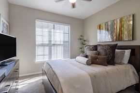 Midland apartment for rent - A bedroom with a bed, a television, and a painting on the wall.