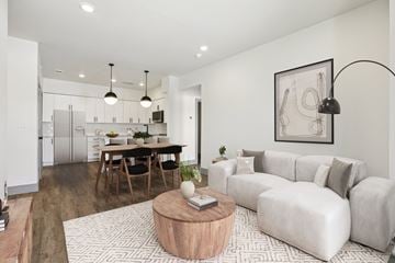 Austin condo for rent - A modern living room with a grey sofa, wooden coffee table, and a dining table with chairs.