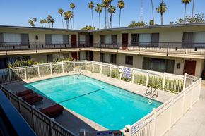 Los Angeles apartment for rent - A pool surrounded by a white fence and red lounge chairs.