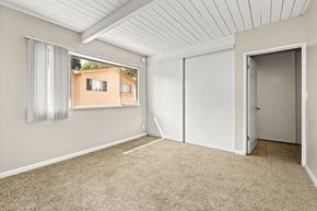 Los Angeles apartment for rent - A room with a carpeted floor and a window showing a building outside.