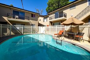 Los Angeles apartment for rent - A swimming pool in a residential area with a sun umbrella and chairs.