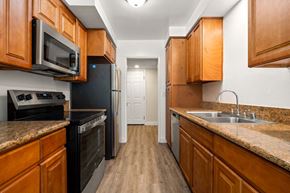 Encino apartment for rent - a kitchen with wooden cabinets and black appliances at White Oak Terrace Apartments, Encino, California