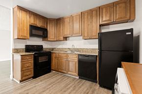 Canoga Park apartment for rent - a kitchen with black appliances and wooden cabinets at Parthenia Terrace Apartments, California, 91304