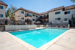 Encino apartment for rent - A swimming pool in front of a building with a black fence around it.