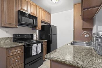 A kitchen with black appliances and granite counter tops