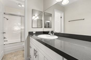 A bathroom with a sink, mirror, and a shower.