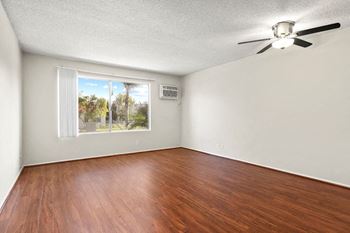 An empty living room with a window and a ceiling fan
