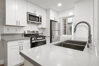 A modern kitchen with white cabinets and stainless steel appliances.